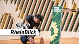 Ein Handwerker scharibt die letzten Schrauben in das Parteitagspodium der Grünen