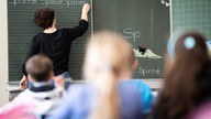 Eine Lehrerin schreibt in einer Grundschule an Tafel