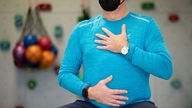 Atemtraining in einer Reha-Klinik: Ein Mann hält seine Hände auf Bauch und Brust.