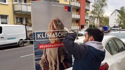 Ein Mann hängt ein Wahlplakat der Partei SPD auf 