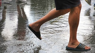 Nach einem kurzen Sommergewitter mit kräftigen Regenfällen laufen Personen durch die Pfütze