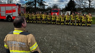 Feuerwehrleute in Bergisch Gladbach stehen aufgereiht im Innenhof.