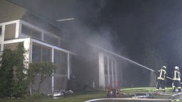 Zwei Feuerwehrleute löschen den Brand eines Wohnhauses in Issum