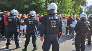 Polizisten stehen Fußballfans gegenüber. 