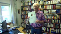 Priester Herbert Kaeufer hält ein Dokument in der Hand.