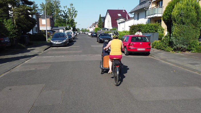 Eine Fahrradfahrerein auf einer Straße in einem Wohngebiet.