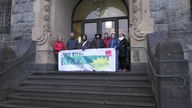 eine Gruppe von Erzieherinnen steht mit Spruchband vor dem Remscheider Rathaus