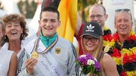 Ein Foto eines glücklichen Goldmedaillensiegers der Reit-EM. Neben ihm steht seine Familie und Freunde.