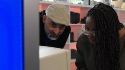 Nihat Sevinc und Precious Mutombo blicken in einen alten Computer