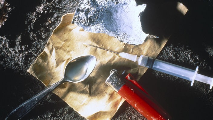 Drogenbesteck für den Herion-Konsum bestehend aus einem Löffel, Feuerzeug, einer Spritze, Alluminiumfolie und einem Stück Papier.