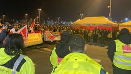Viele Menschen mit gelben Westen und Bannern, im Hintergrund ein weißer Streik-Pavillon