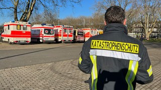 Mann vom Katastrophenschutz steht vor Krankenwagen