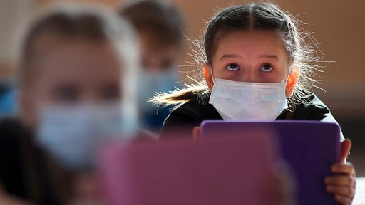 Mädchen mit Mundschutz schaut auf ein Tablet (Ivanovo, Russland)