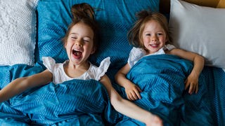 Überkopf-Shot von zwei Schwestern, die in einem Bett liegen