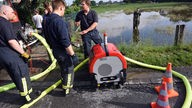 Feuerwehrleute legen am 02.06.2016 in Hamminkeln  auf einer vom Fluss Issel überfluteten Wiese Schläuchen zum Abpumpen