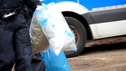 Polizisten halten in Tüten verpacktes Marihuana