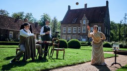 Eine Szene vom Set der Serie: Eine Frau wirft einen Ball und drei Männer schauen zu