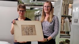 Projektleiterin Dr. Christiane Rühling (links, Landesbibliothek Detmold) und Kunsthistorikerin Isabelle Christiani mit einer der Zeichnungen