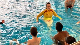 Eine Schwimmlehrerin von der DLRG mit Kindern im Schwimmbecken.