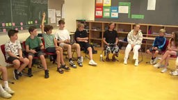 Die Schüler, die Lehrerin und der Medien-Scout sitzen in einem Stuhlkreis zusammen.
