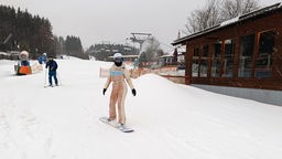 Eine Frau auf einem Snowboard auf der Piste.