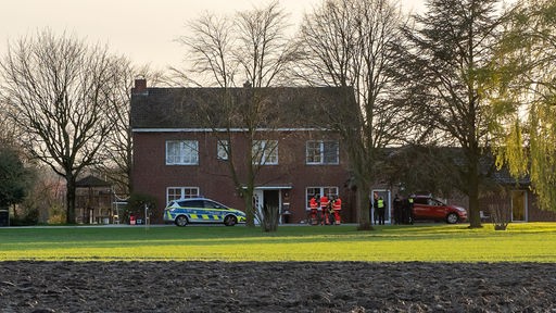 Ein Polizeiwagen und Rettungskräfte vor einem Einfamilienhaus.