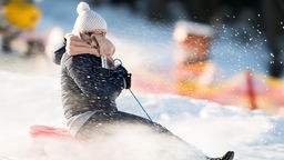 Ein Frau fährt in Winterberg auf einem Schlitten