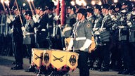 Mit Fackeln und Musikinstrumementen stehen Bundeswehrsoldaten 1999 während des Großen Zapfenstreichs im Schlosses Bellevue