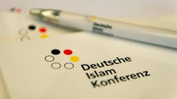 Pressemappen und ein Kugelschreiber mit der Aufschrift "Deutsche Islam Konferenz"