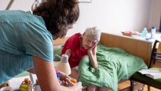 Pflegerin Ramona Rössner schneidet beim ambulanten Besuch ihrer Patientin, der 97-jährigen pflegebedürftigen Seniorin Brigitte Richter, Obst für eine Zwischenmahlzeit.