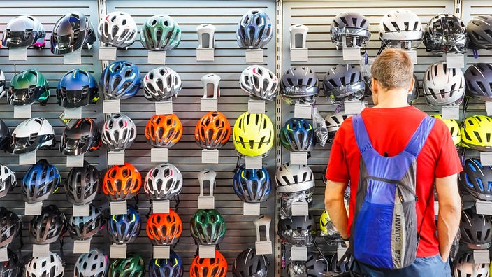 Čovek u prodavnici razgleda biciklističke šlemove