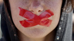 Devojka sa nalepljenom crvenom trakom preko usta