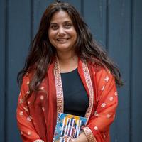 Autorin Mithu Sanyal hält lächelnd ihr Buch 