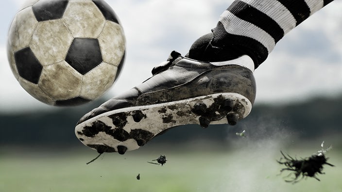 Großaufnahme eines Fußball-Schuhs, der den Ball trifft.
