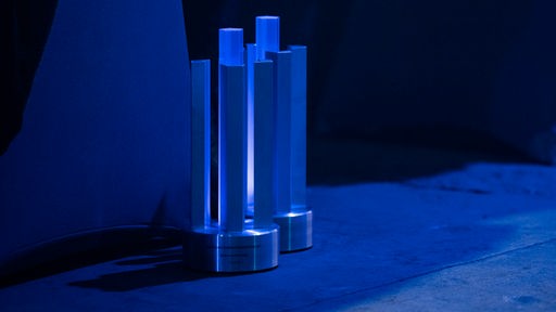 Zwei Preise stehen auf dem Boden bei der Vergabe des Deutschen Computerspielpreises am 11.05.2023.
