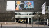 An dem Gebäude hängt ein Banner mit Kunst von Hilma af Klint und Wassily Kandinsky