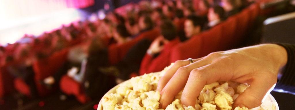 Voller Kinosaal und Gast mit Popcorn