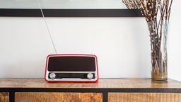 Ein roter Retro-Radioplayer auf Holzschrank in einem Wohnzimmer