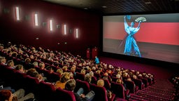 Das Publikum im Kino verfolgt die Übertragung einer Oper auf einem Bildschirm an.