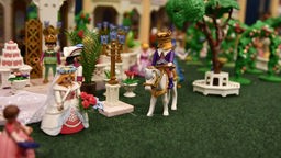 Eine männliche Playmobil-Figur mit Krone reitet auf einem Schimmel zu einer weiblichen Playmobil-Figur mit Blumenstrauß und Schleier.