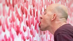 Künstler aus Düsseldorf malt ein Bild mit seiner Zunge.