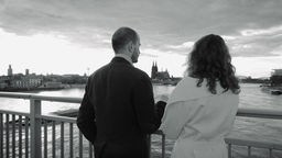 ein Pärchen steht, nach Norden schauend auf der Sevrinsbrücke in Köln, von hinten fotografiert, schwarzweiß