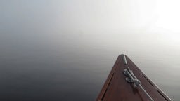 Spitze eines kleinen Bootes, das bei Nebel auf einem See treibt.