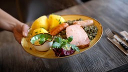 Symbolbild Restaurant: Ein Teller mit Feisch und Gemüse;  2024 steigt die Mehrwertsteuer in der Gastronomie von sieben auf 19 Prozent.