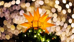Ein leuchtender Weichnachtsstern auf der Spitze eines geschmückten Weihnachtsbaums