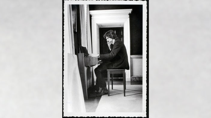 Ein Schwarz-Weiß Portrait von Nick Drake, wie er rauchend am Klavier sitzt.