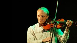 Portrait von dem Kinderliedermacher Toni Geiling währrend er auf seiner Geige spielt.
