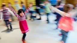 Symbolbild: Kinder tanzen bei einer Musikstunde durch einen Raum im Kindergarten