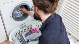 Ein Mann füllt seine Waschmaschine mit Badetüchern