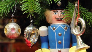 Ein Lichterbergmann steht am 29.11.2012 im Spielzeugmuseum unter einem Weihnachtsbaum mit historischem Glasschmuck.